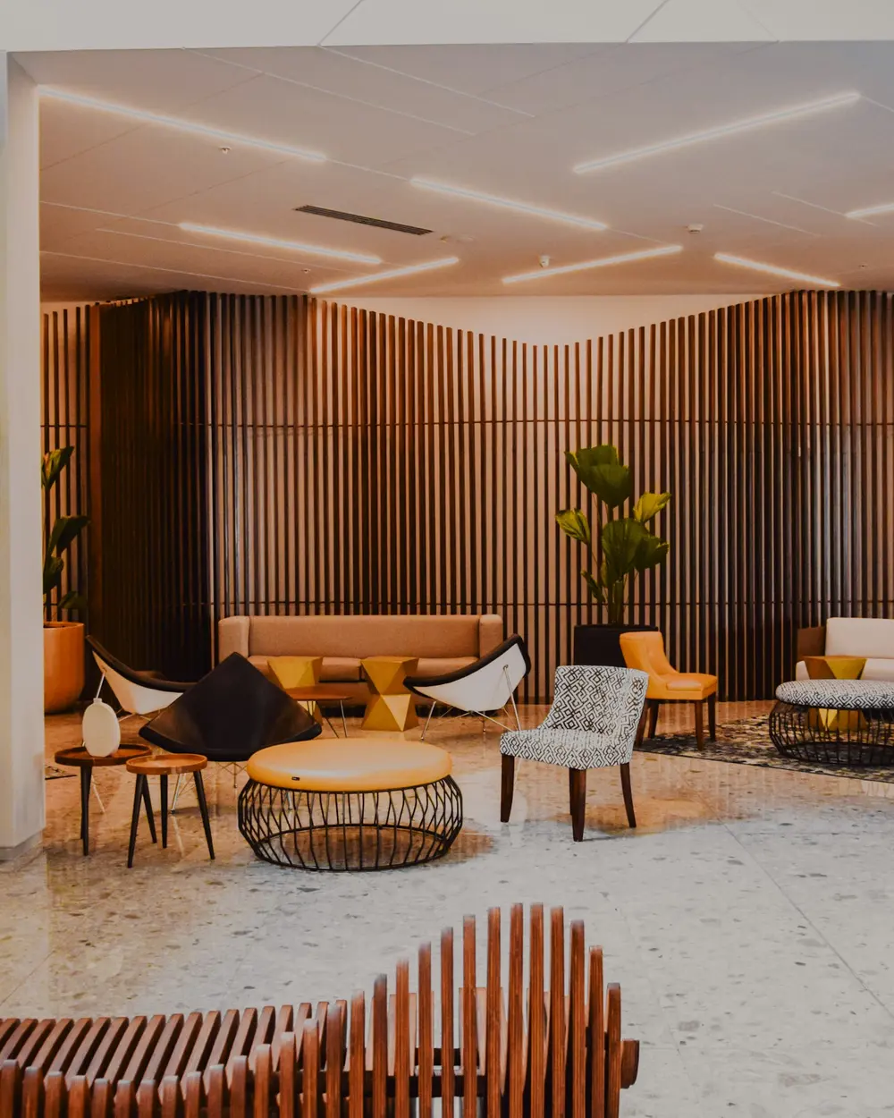 Ahşap kaplamalı, oturma gruplarıyla düzenlenmiş modern bir otel lobisi